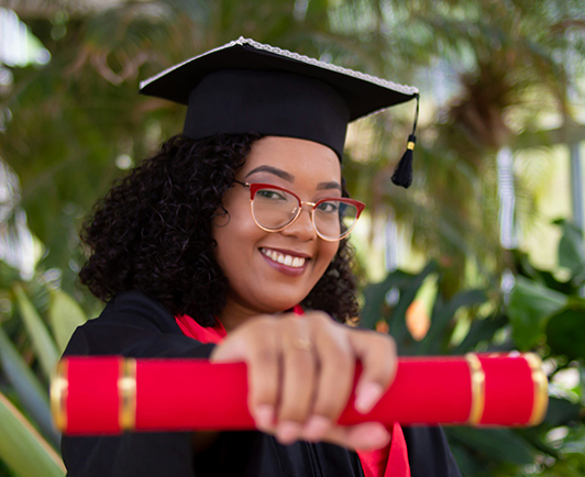 A graduate in cap and gown holding a diploma