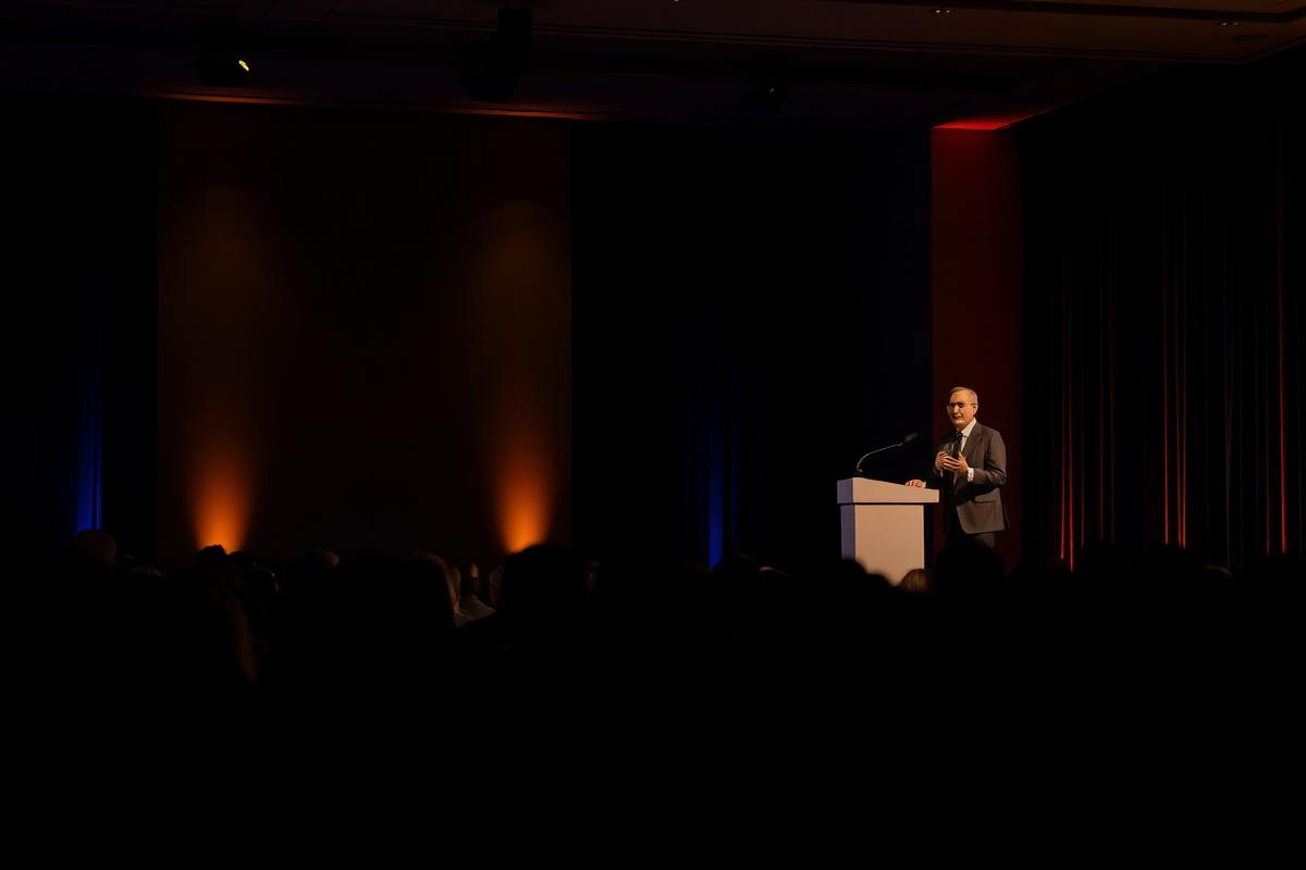 A speaker addressing an audience from a lectern