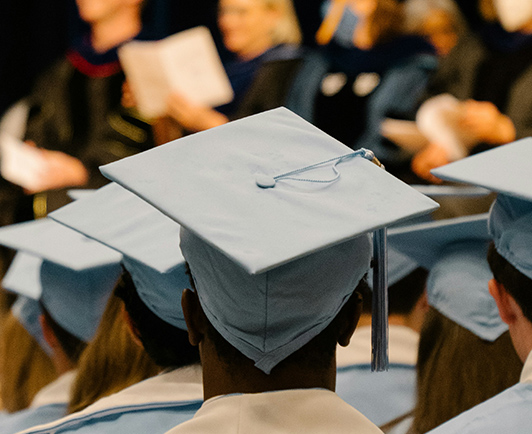 Graduates seated in caps and gowns at a commencement ceremony